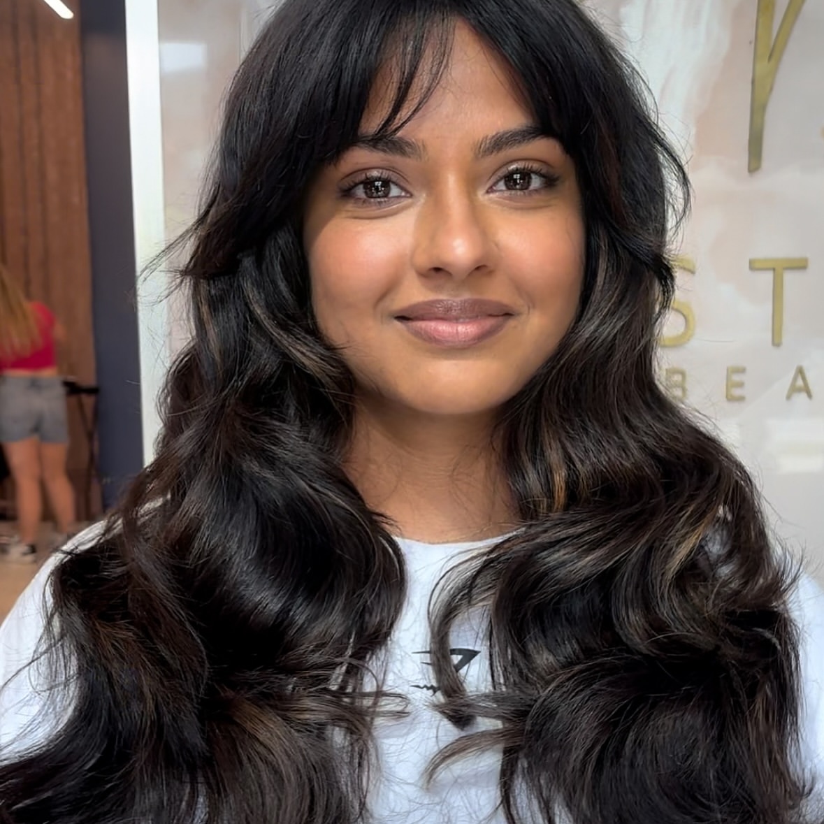 Warm face-framing balayage on dark wavy hair